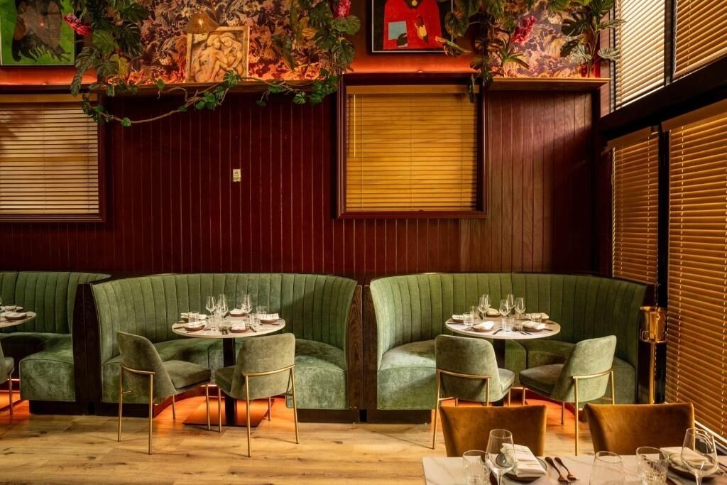 Ein Restaurant mit grünen Sitzbänken, runden Tischen und einer gemütlichen Atmosphäre.