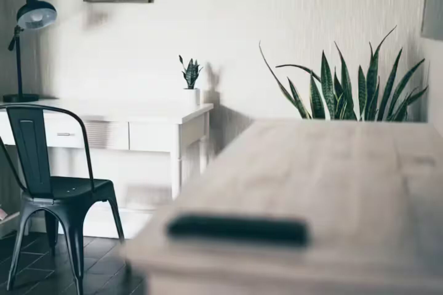 A modern room with a desk, a chair, a potted plant, and a lamp.