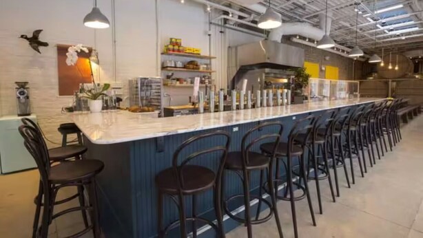 Un'area bar con un lungo bancone, diversi sgabelli e lampade pendenti.