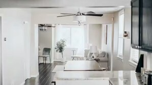 Una cucina moderna con pavimento scuro, mobili bianchi e una ventola a soffitto.