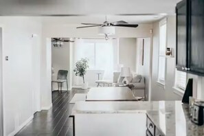 Una cocina moderna con suelo oscuro, armarios blancos y un ventilador de techo.