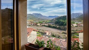 Vistes des d'una finestra sobre una vall amb cases i muntanyes.
