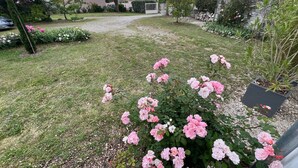A garden with pink roses, a gravel path, and a stone wall. - Guest Room “Chambre De Lucie” with Private Terrace, Garden, and Wi-Fi (Bourcefranc-le-Chapus)