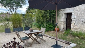 An outdoor seating area with a table and chairs, a large umbrella, and a potted plant. - Guest Room “Chambre De Lucie” with Private Terrace, Garden, and Wi-Fi (Bourcefranc-le-Chapus)