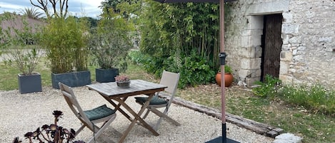 An outdoor seating area with a table and chairs, a large umbrella, and a potted plant.