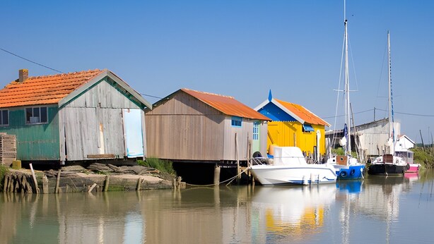 A calm waterway with wooden buildings and boats. - Guest Room “Chambre De Lucie” with Private Terrace, Garden, and Wi-Fi (Bourcefranc-le-Chapus)