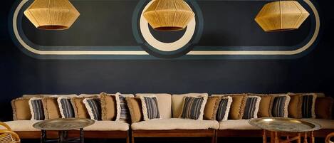 Un intérieur moderne avec un canapé, deux tables rondes et trois lampes suspendues.