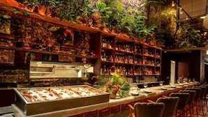 A bar with a long counter, shelves of bottles, and a display case with food items. - Deluxe King | The Daydrift | Rooftop Pool, Quiet Center, Slow Down (Miami Beach)