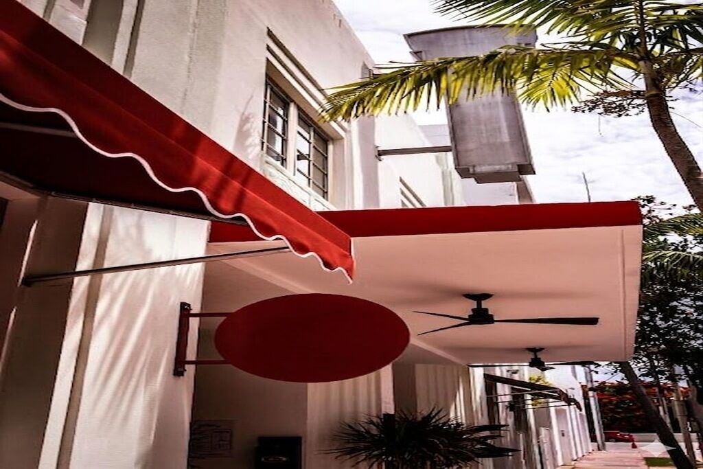 A building with a red awning, a ceiling fan, and a palm tree in the background.