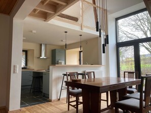 Eine moderne Küche mit Essbereich, Holzboden und großen Fenstern.
