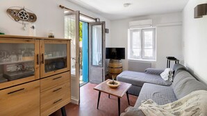 A room with a wooden cabinet, a sofa, a small table, and a television. - Cottage 'Le Saulou' with Private Terrace and Private Garden (Sarlat-la-Canéda)