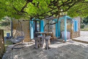A rustic outdoor seating area with a hanging chair, a table, and chairs under a tree. - Cottage 'Le Saulou' with Private Terrace and Private Garden (Sarlat-la-Canéda)