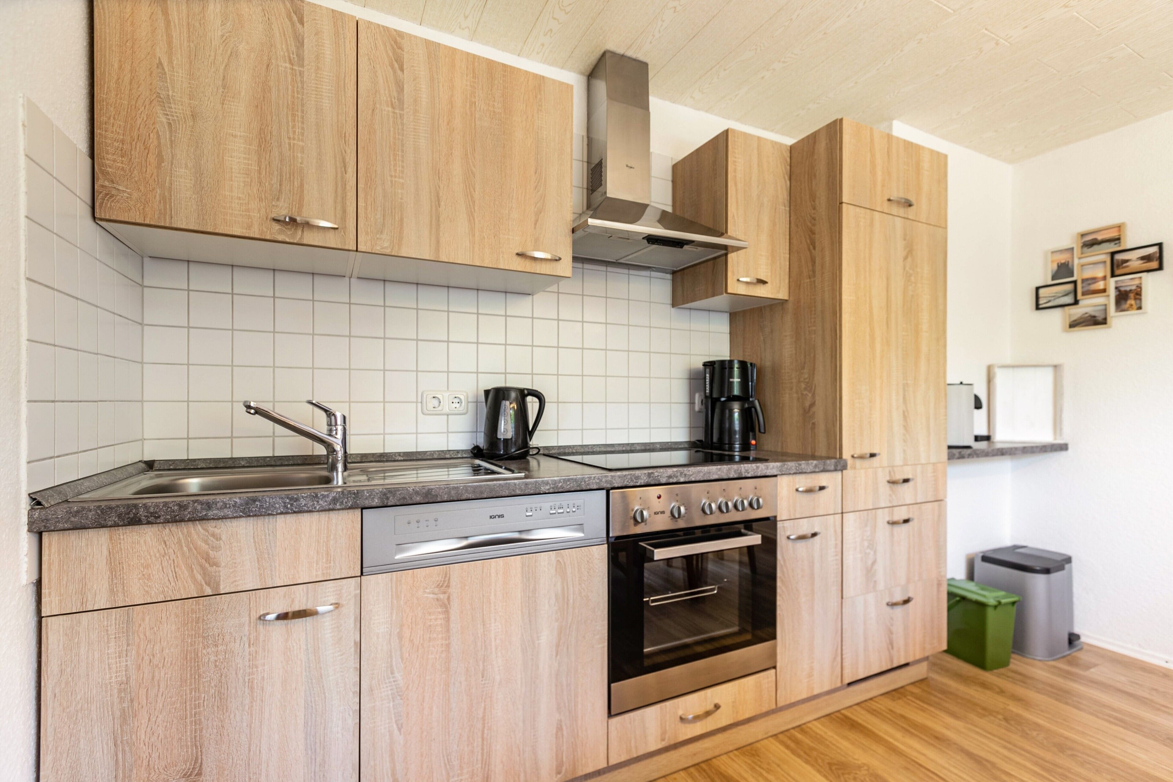 A modern kitchen with wooden cabinets, a stainless steel oven, a dishwasher, and a coffee maker.