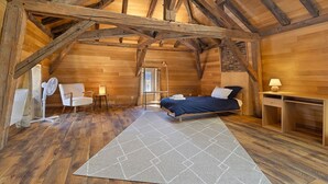 Ein Schlafzimmer im Loft-Stil mit Holzbalkendecke, einem Bett, einem Schreibtisch und einem Stuhl.