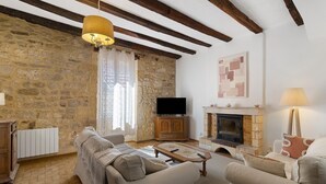 Ein Wohnzimmer mit Steinwänden, Kamin, Fernseher und einer Couch.