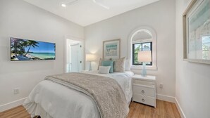 Un dormitorio con cama, mesitas de noche, una ventana con persianas y una puerta.