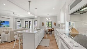 Una cocina moderna con una isla central, armarios blancos y un comedor con mesa y sillas.