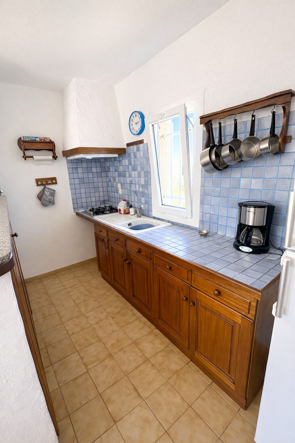 Una cocina con armarios de madera, un fregadero, una ventana y una cafetera.