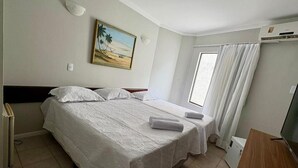 A hotel room with a bed, a desk, a TV, a painting, and a window with curtains. - BREEZE HOTEL (Natal)