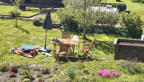 A patio with a table and chairs, a small umbrella, and a solar-powered device. - Spacious vacation apartment with special flair and beautiful views in Glaadt (Jünkerath)