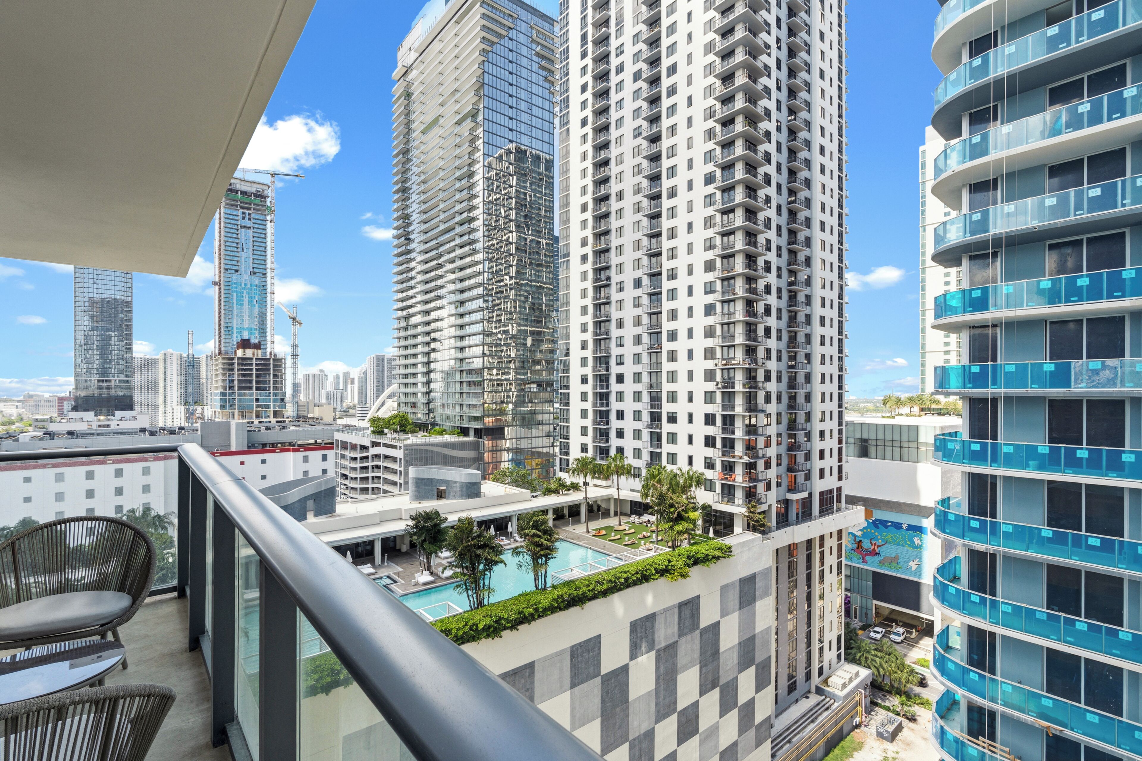 A high-rise building with a pool, balconies, and a view of the cityscape.