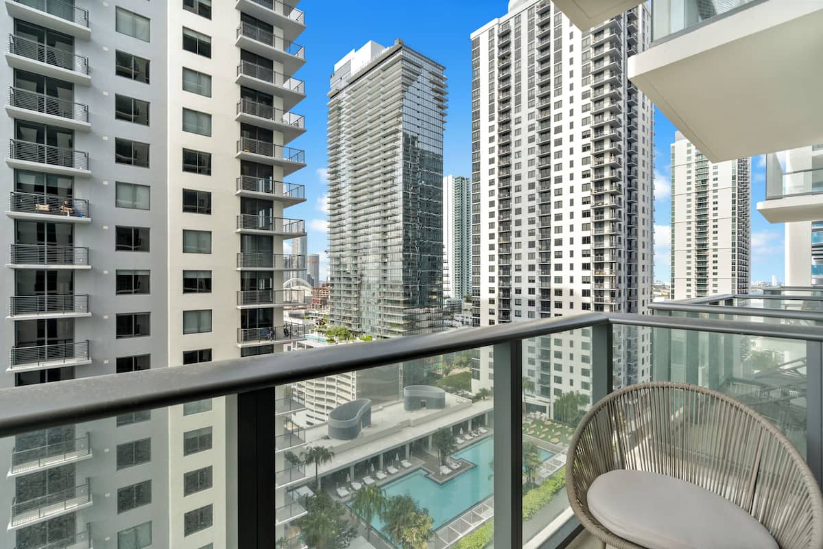 Un immeuble de grande hauteur doté de nombreux balcons, d’un espace piscine et offrant une vue sur d’autres immeubles de grande hauteur.