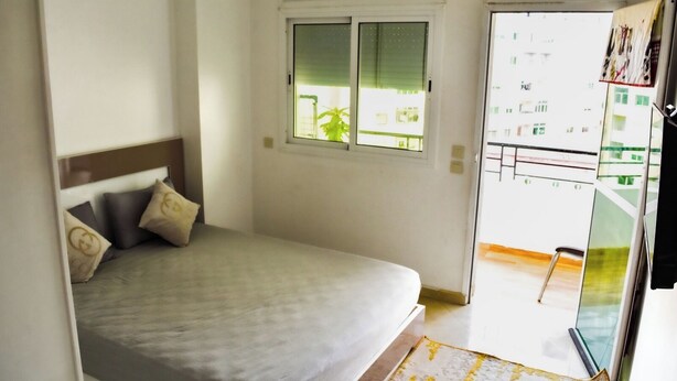 A bedroom with a bed, a window, and a view of a balcony. - Dream apartment tanger (Tanger)
