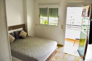 Een slaapkamer met een bed, een raam en uitzicht op een balkon.