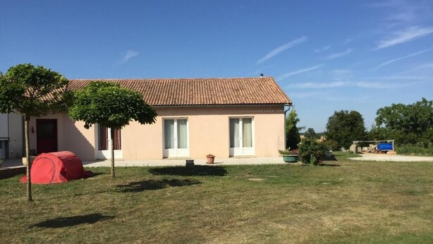 Un bâtiment d’un seul étage, doté d’un toit recouvert de tuiles, d’un petit porche à l’avant et d’une cour gazonnée.