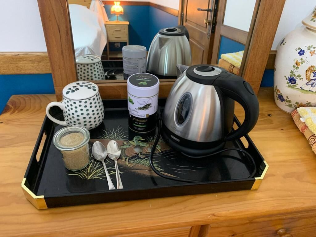 A tray with a kettle, a mug, a jar, and spoons on a wooden table.