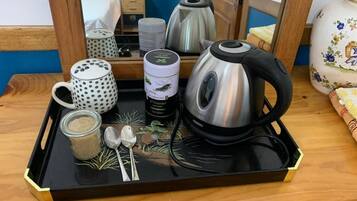 A tray with a kettle, a mug, a jar, and spoons on a wooden table.