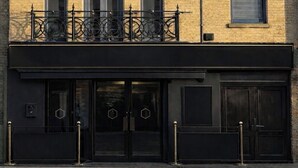 Un edificio de varios pisos con fachada de ladrillo, múltiples ventanas y barandilla de metal negro.