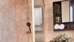 Un baño con ducha, lavabo y espejo.