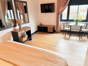 Ein Zimmer mit einem Bett, einem Schreibtisch, einem Stuhl, einem Fernseher und einem Fenster mit Vorhängen.