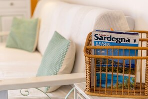 A wicker basket with a magazine on a white sofa with patterned cushions. - Apartment 'Smeraldina' with Private Terrace, Wi-Fi and Air Conditioning (Alghero)