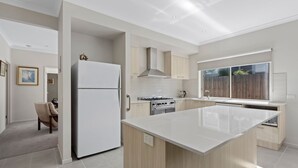 Una cocina moderna con una isla central, horno empotrado y un amplio ventanal.