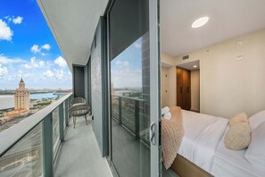 Un balcon donnant sur le paysage urbain, un lit avec une couverture et une chaise.