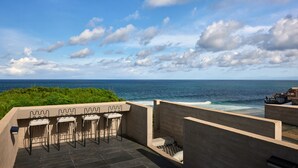 A terrace with outdoor seating overlooking the ocean. - Orama Bali (Pecatu)