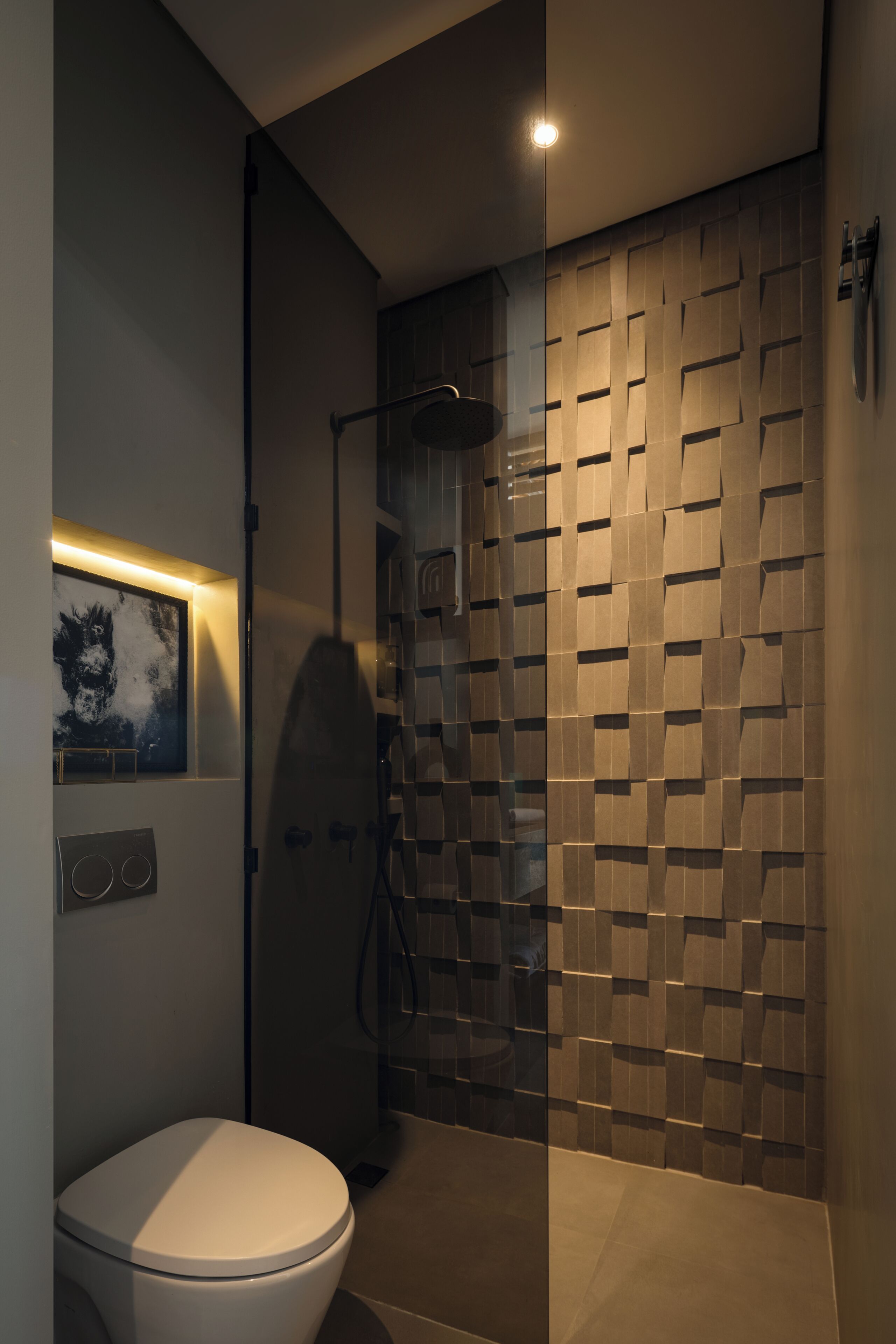 A modern bathroom with a toilet, shower, and a wall with a geometric pattern.