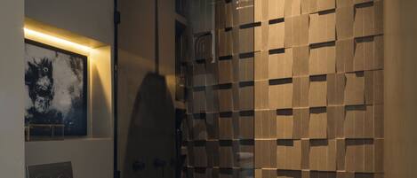 A modern bathroom with a toilet, shower, and a wall with a geometric pattern.