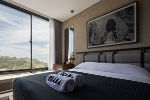 A hotel room with a large bed, a view of the outdoors, a framed picture on the wall, and a nightstand with a lamp. - Orama Bali (Pecatu)