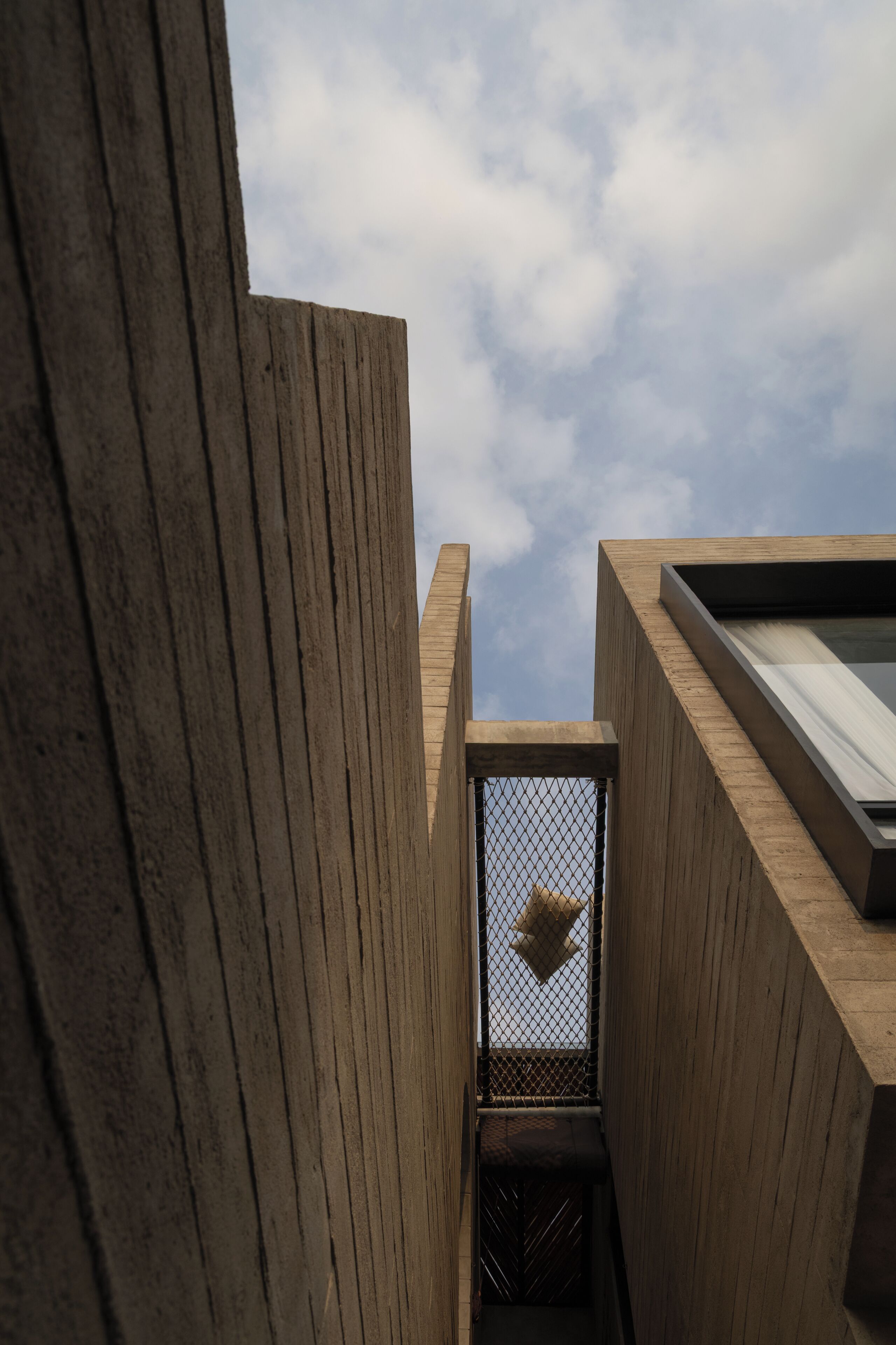 A modern building with a wooden facade and a metal mesh window.
