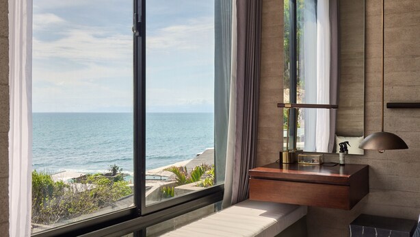 A modern bathroom with a large window, a vanity, a mirror, and a ceiling light. - Orama Bali (Pecatu)