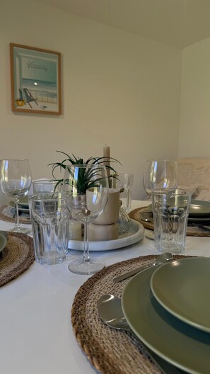 A dining table set with clear glassware, plates, and a centerpiece with a plant. - Mazet Noa - Quiet terrace & pool (Le Rouret)
