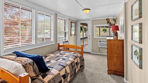 Une chambre à coucher comprenant un lit, une commode, une chaise et une porte donnant sur un balcon.