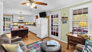 Une cuisine moderne avec des meubles blancs, un îlot central et un ventilateur de plafond.