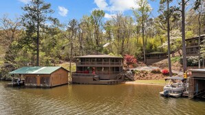 Un chalet au bord du lac, doté d’un quai, d’une terrasse couverte et d’un bateau.