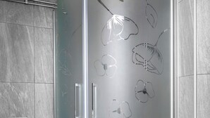 Een badkamer met een douchecabine van glas, een wit toilet en een vloer van marmer.