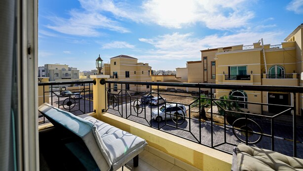 Un balcon donnant sur un parking et des immeubles.