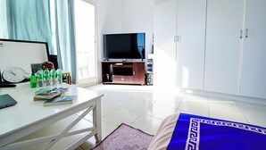 Une chambre équipée d’un bureau, d’une télévision, d’une armoire et d’une horloge.